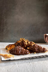 Dark chocolate croissants with nut and flower of salt on top in vintage dark stone background. Tasty and freshly croissants. 