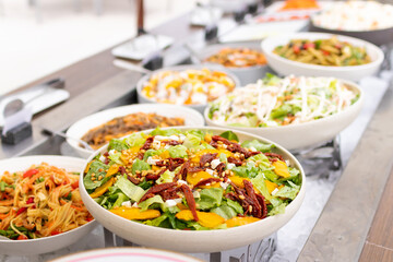 Assorted fresh salads displayed on a buffet in individual containers at garden restaurant.