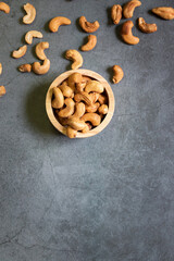 Cashew nuts in wooden bowl on dark table background with copy space, top view.