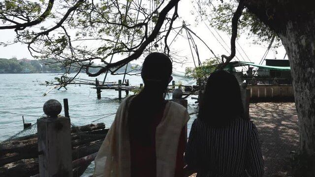 Tourists Indian Mother and daughter walking along the sea shore in Fort Kochi beach on summer vacation Kerala India 4K slow motion video footage. outing  in coastal region walkway.