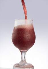 Red beer filling a glass of red beer, gray gradient background, selective focus.