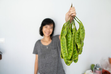 Close up of petai held by Asian woman on beige background