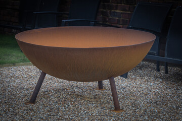 A Large Steel Fire Pit with Rust standing on three legs