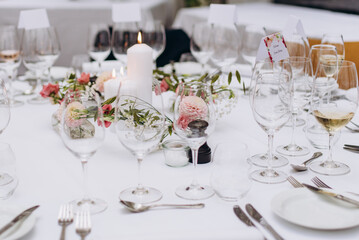 Wedding reception table in the restaurant decorated with white candles and flowers.