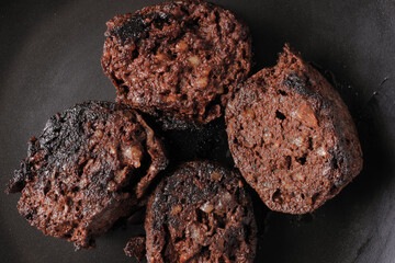Detail of a portion of grilled onion blood sausage with black background