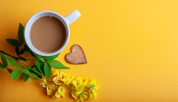 Song of the morning on the yellow.Close-up of a cup of coffee with milk on the table, to decorate the heart and yellow flowers,