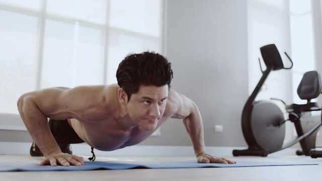 Man athletic trainer doing push up in gym And live teaching via laptop Or video call. Exercise strengthens the muscle. Workout take care of your health be in good shape. Distance teaching technology 