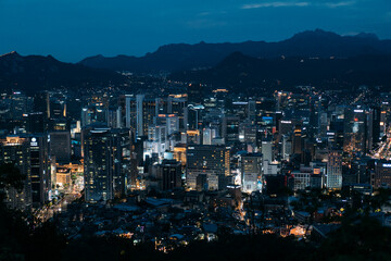 Fototapeta na wymiar Cityscape of Seoul, South Korea lit up at dusk, with Mountains behind.
