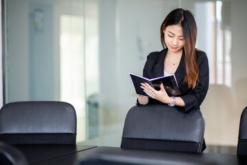 Portrait of asian young business woman sitting in office with notebook