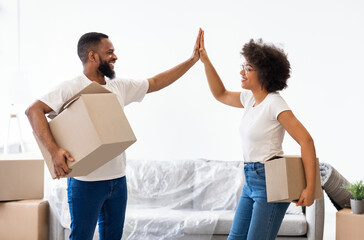 Couple Giving High-Five Holding Packed Boxes Ready To Move Home