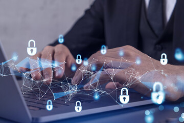 A programmer is typing a code on computer to protect a cyber security from hacker attacks and save clients confidential data. Padlock Hologram icons over the typing hands. Formal wear.