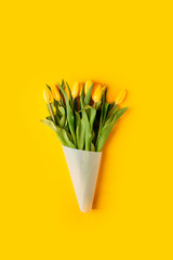 Yellow tulip flowers bouquet on yellow background. Flat lay, top view, copy space. Banner for seasonal holiday, springtime concept, International Woman day, 8 march, Happy Easter greeting card