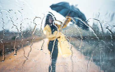 Young woman walking with her umbrella and raincoat on a rainy day

