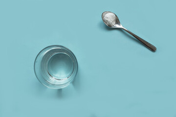 collagen soluble powder in spoon  and water glass on a light blue background