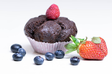 Baked chocolate muffin with juicy berries, strawberries, blueberries, raspberries.