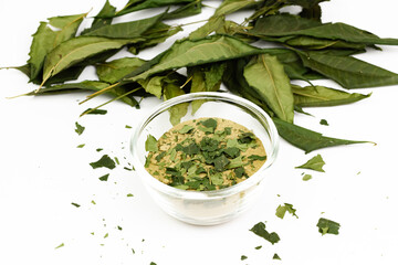 Neem powder in transparent bowl and dried neem leaf isolated on white background.