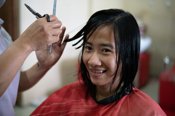 Beautiful young woman getting her haircut by a hairstylist at a salon