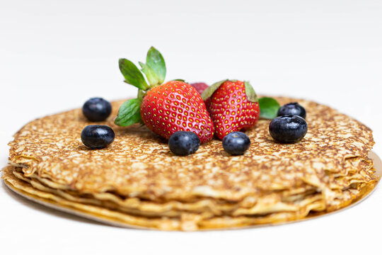 Ripe juicy strawberries and blueberries lie on a delicious pancake. Russian cuisine national dish bliny with fresh berries.