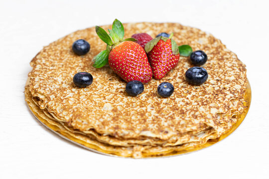 Ripe juicy strawberries and blueberries lie on a delicious pancake. Russian cuisine national dish bliny with fresh berries.