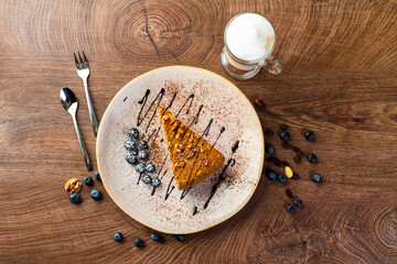 a piece of honey cake on a plate, decorated with chocolate and blueberries 