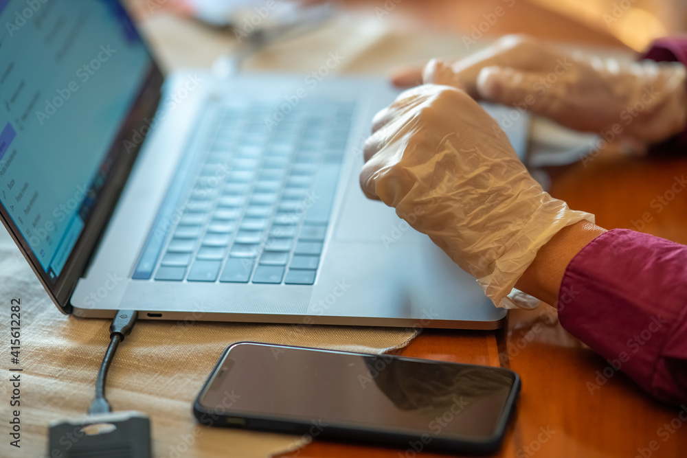 Poster man using laptop computer at home wearing gloves in pandemic time, detail on hands and keyboard
