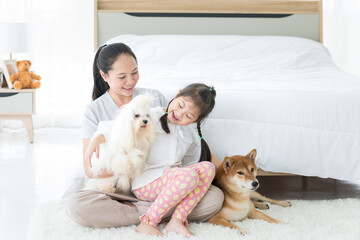 A mother whose daughter was playing with a white-haired maltese and had a Shiba Inu by her bed.