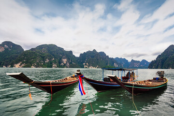 Fototapeta na wymiar Long-tailed boat group floating on the asia lake in the among the islands with mountains in background at Surat Thani Province of Thailand.