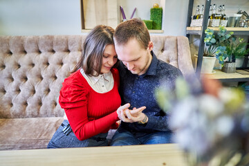 Smiling couple sitting on sofa looking at hands