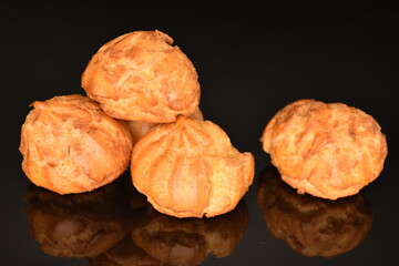 Several fresh fragrant chouquettes, on a black background.