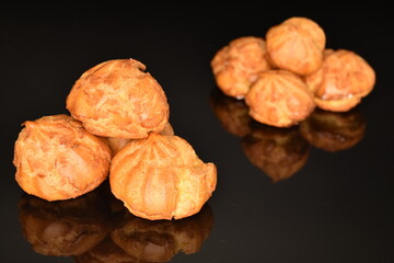 Several fresh fragrant chouquettes, on a black background.