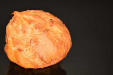 One tasty fresh Chouquettes, macro, on black.