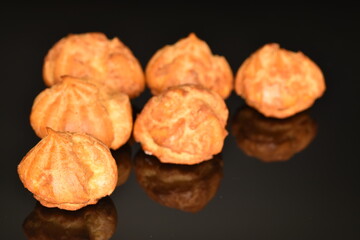 Several fresh fragrant chouquettes, on a black background.