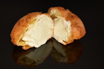 One fragrant cut in half Chouquettes, close-up, on a black background.
