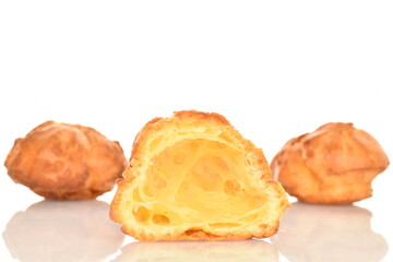Half fresh chouquettes in focus, macro and two whole on a white background.