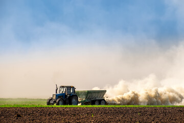Tractor spraying fertilizer on the soil early spring time. Maintaining soil fertility, improving crop development