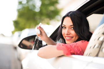 woman driving car looks out the window and shows keys to camera