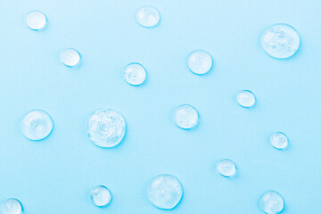 Liquid gel cosmetic on blue. Texture of gel on blue background. Pattern of transparent drops gel for face cleansing. Moisturizing cosmetic beauty product for skincare. Lotion or serum for skin care