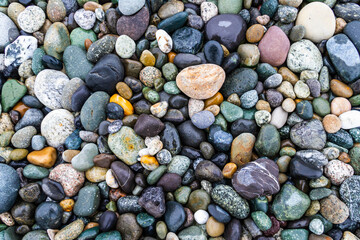 Colorful smooth rocks on the beach covered in water.