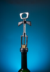 Chromed corkscrew on the neck of the bottle on a blue background. concept of rare expensive wine....