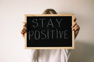 Woman holding a chalkboard with stay positive sign. Motivation.