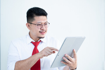 Expert in digital technologies. Cheerful young man in formal wear working on digital tablet and smiling while standing isolated on white background