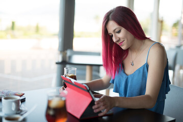 Pretty woman looking tablet while drinking coke