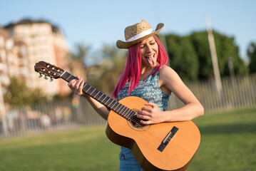 happy spanish women play the guitar at sunset in a park on a spring day