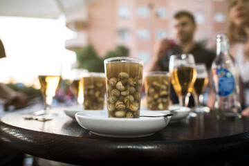 Spanish people eats a glass of snails in sauce on the terrace of a bar