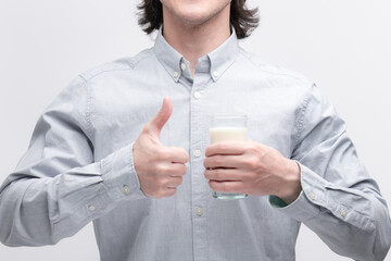 Man drinking milk from a glass and showing thumb up gesture. Healthy lifestyle concept