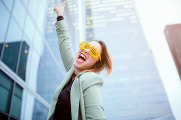 Caucasian woman, with party glasses. Smiling, with an expression of happiness and celebration. In a background of glass buildings. Job, economy, companies, boss woman and businesswoman concept.