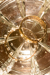 bridal rings on the bottom of a glass of water, bubbles and glitter of light.