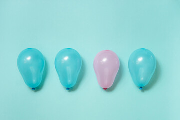 One pink balloon among many blue balloons on blue background. Gender equality concept