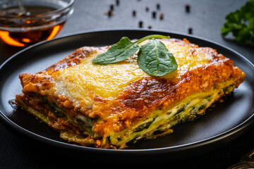Lasagna with pork and spinach on black table
