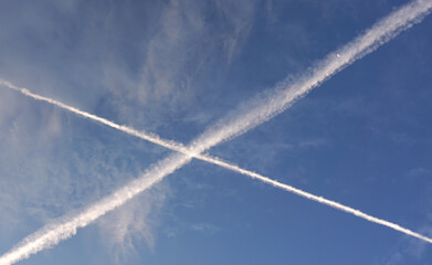 Fototapeta na wymiar Two white trails from commercial airplanes, white moon near - chemtrails conspiracy theory concept